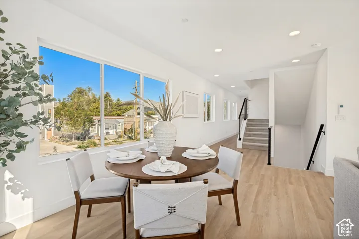 Large picture window, wood-finish flooring, recessed lighting, and staircase with a black metal handrail