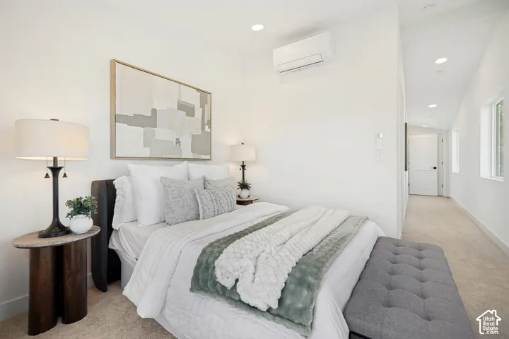 Neutral-toned interior featuring wall-to-wall carpeting, vaulted ceilings, recessed lighting, and a wall-mounted ductless climate control unit