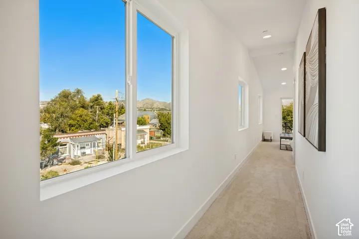 Hallway featuring recessed lighting, carpeting, and multiple windows providing natural light and mountainous scenery