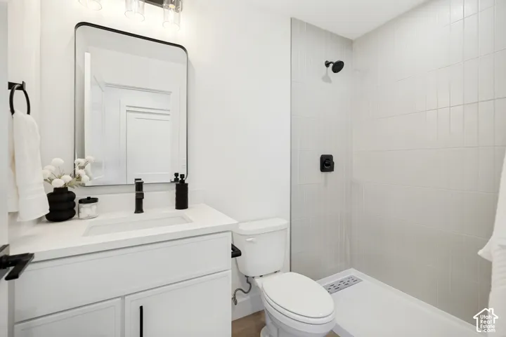 White vanity with a solid surface countertop, rectangular undermount sink, matte black faucet, rectangular mirror with a black frame, and a walk-in shower with vertical wall tile and matte black fixtures