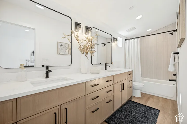 Dual-sink vanity with light wood cabinetry, quartz countertops, matte black fixtures, rectangular undermount sinks, and wall-mounted mirrors with black frames