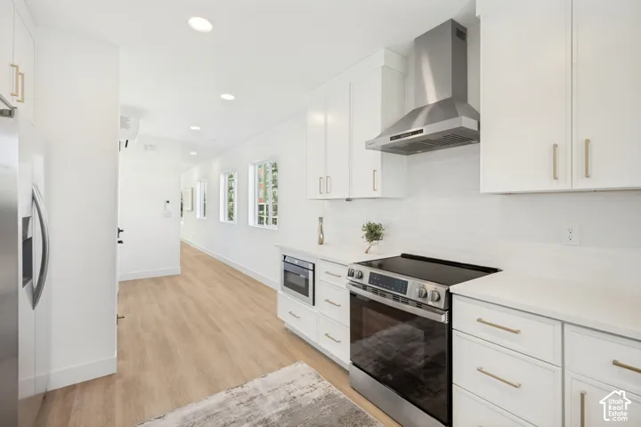 Kitchen featuring white cabinetry, quartz countertops, stainless steel appliances, a built-in microwave, and wood-finish flooring