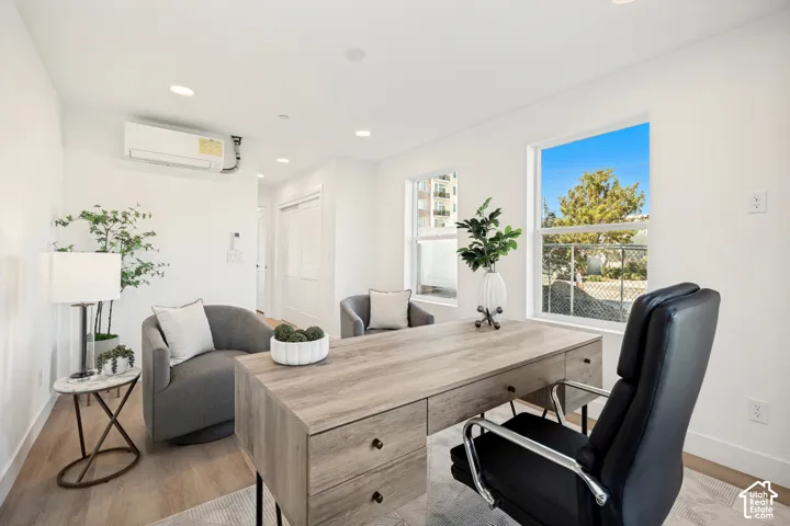 Neutral-toned interior featuring wood-finish flooring, recessed lighting, double-pane windows, and wall-mounted ductless climate control unit