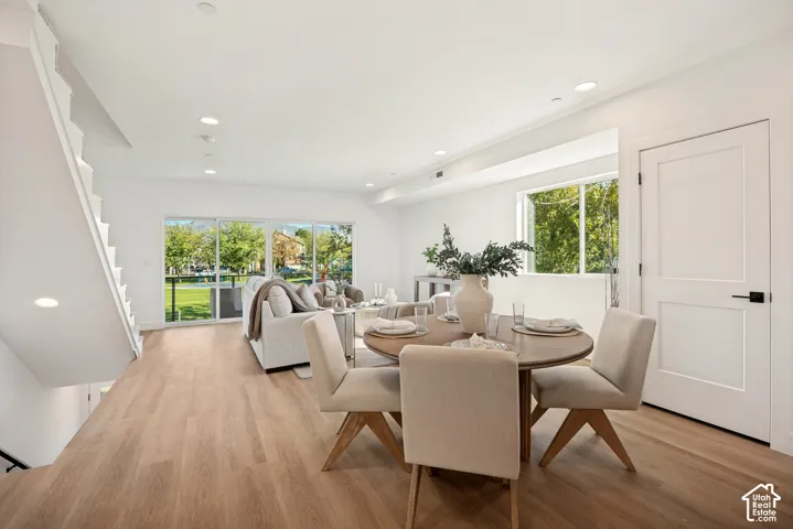 Open-concept interior featuring wood-finish flooring, recessed lighting, sliding glass doors, and a paneled interior door with matte black hardware