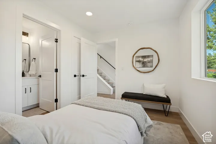 Room interior featuring wood-finish flooring, recessed lighting, white shaker-style interior doors, and a window with natural light