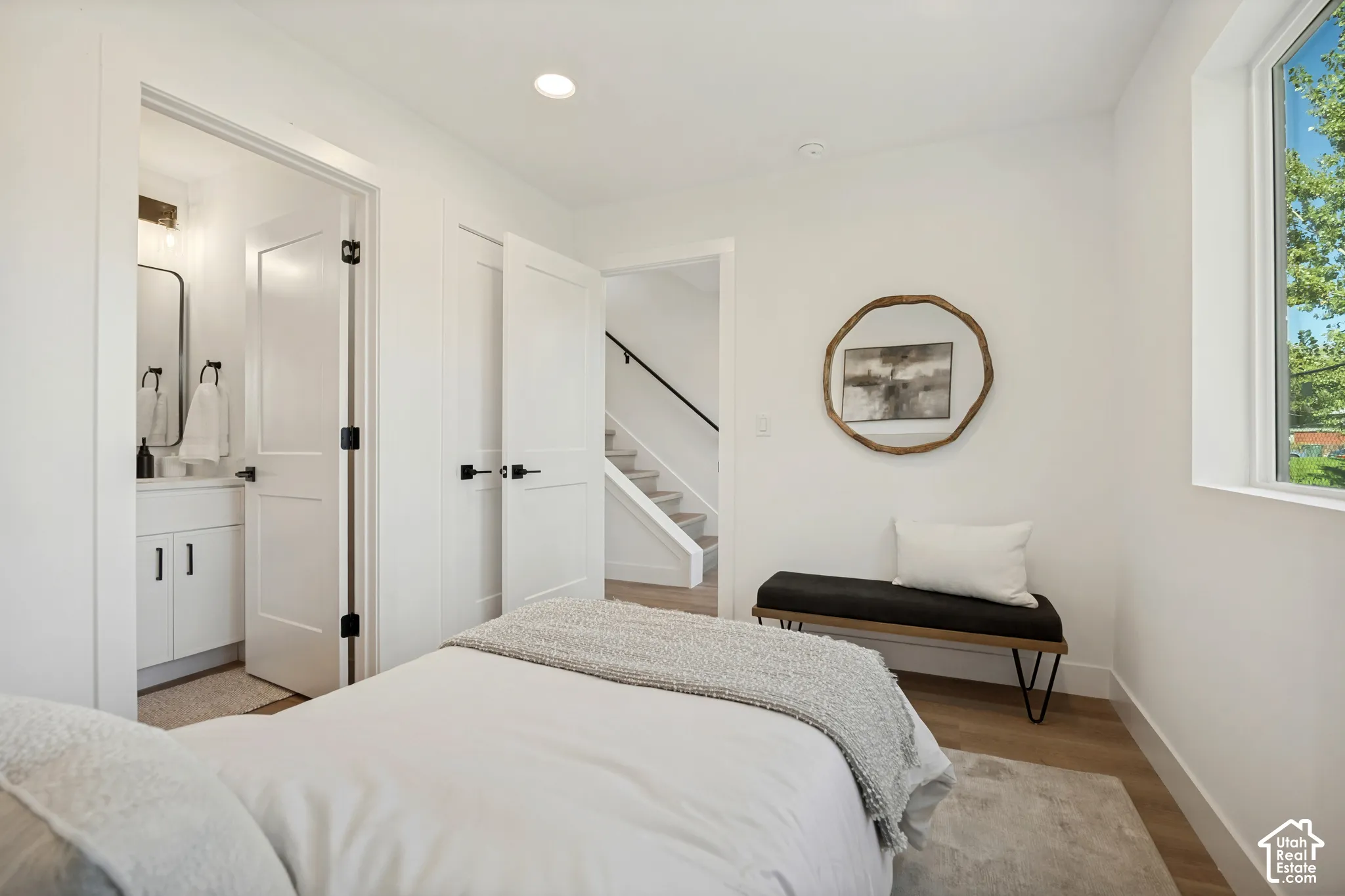 Room interior featuring wood-finish flooring, recessed lighting, white shaker-style interior doors, and a window with natural light