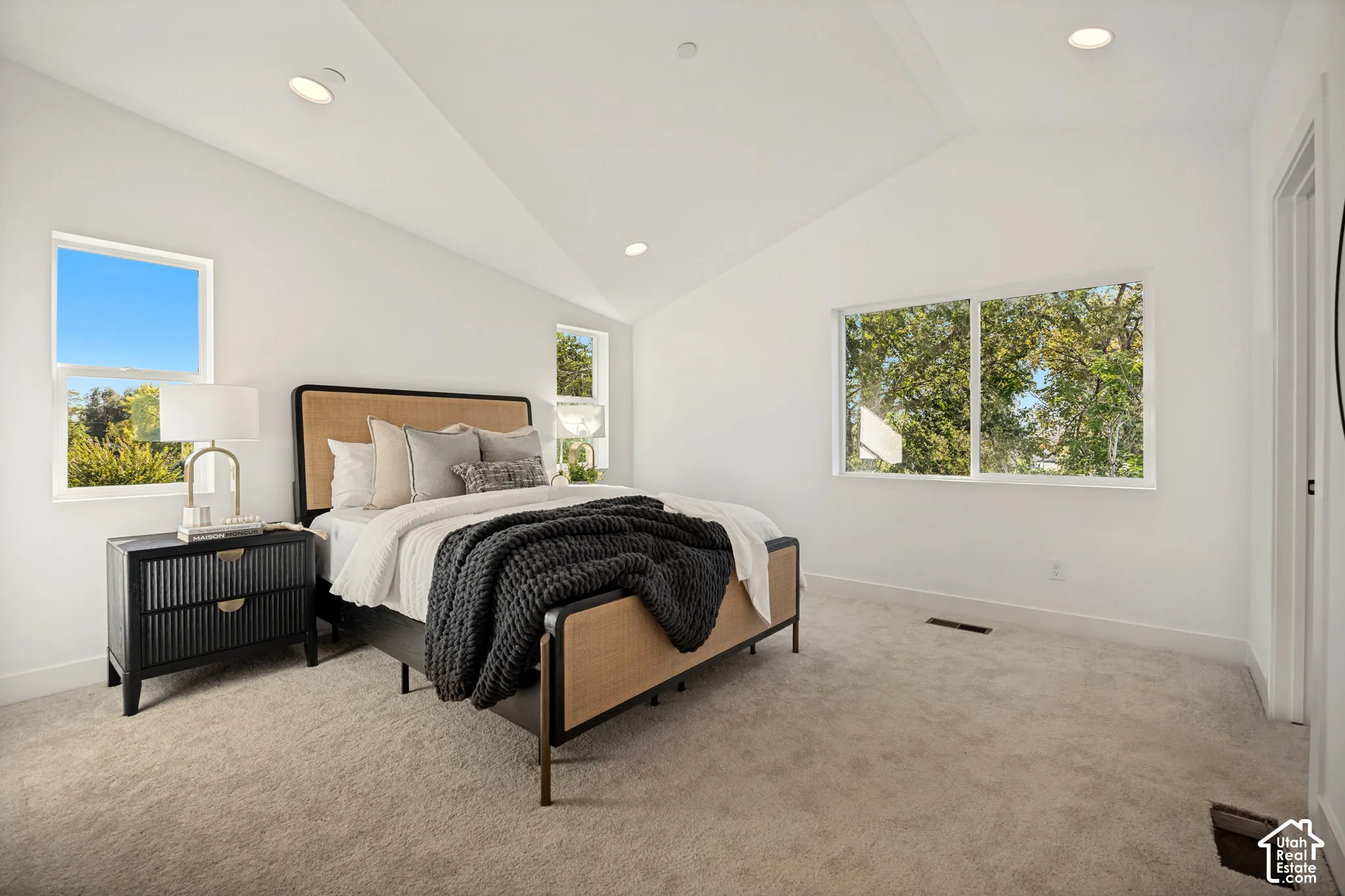 Vaulted ceilings, neutral carpeting, and large windows providing natural light