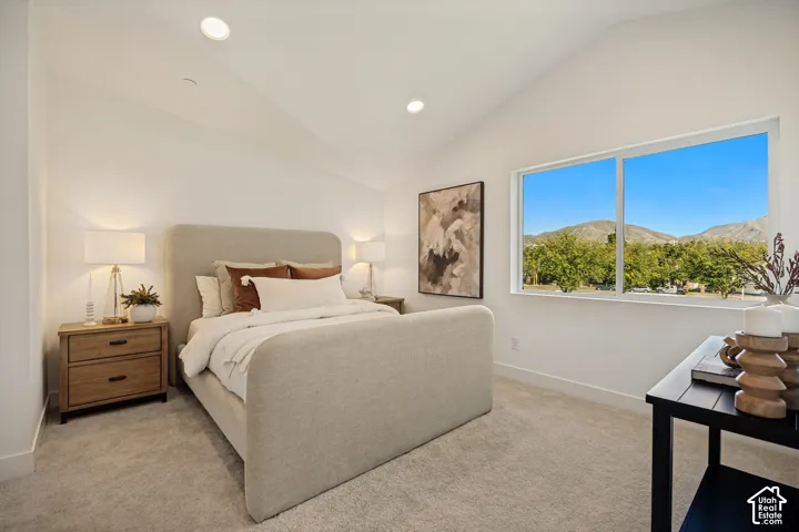 Vaulted ceilings, neutral carpeting, recessed lighting, and a sliding window framing a mountain backdrop