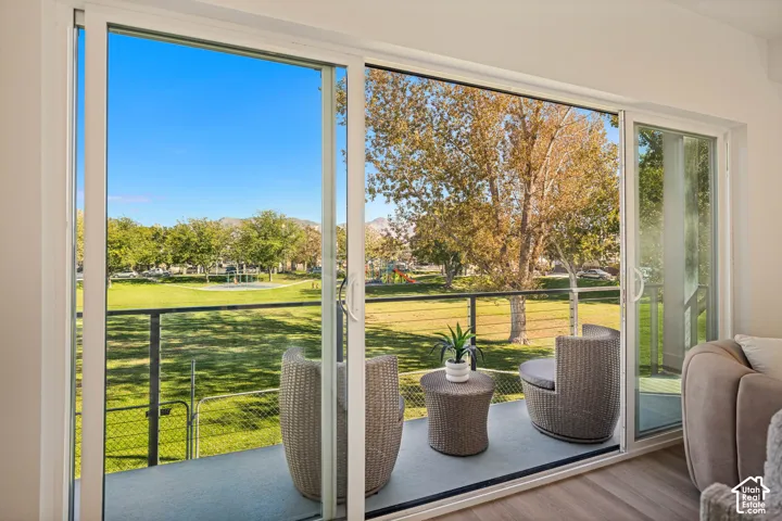 Large glass sliding doors opening to a balcony with metal cable railing and wood-finish flooring