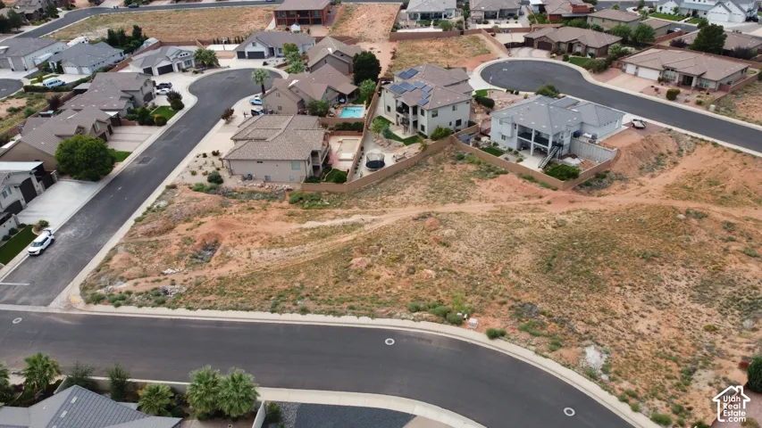 Aerial perspective of a corner lot featuring desert topography, asphalt-paved streets, and access to established utility infrastructure
