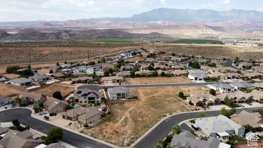 Aerial perspective of a residential development featuring paved cul-de-sac streets, desert landscaping, and prominent mountain range backdrop
