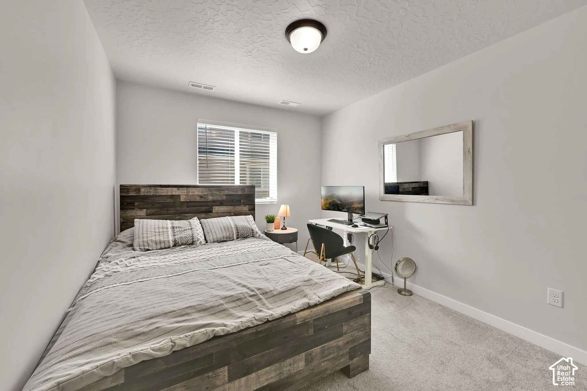 Neutral-toned room featuring wall-to-wall carpeting, a dual-pane window with blinds, and a central ceiling-mounted light fixture