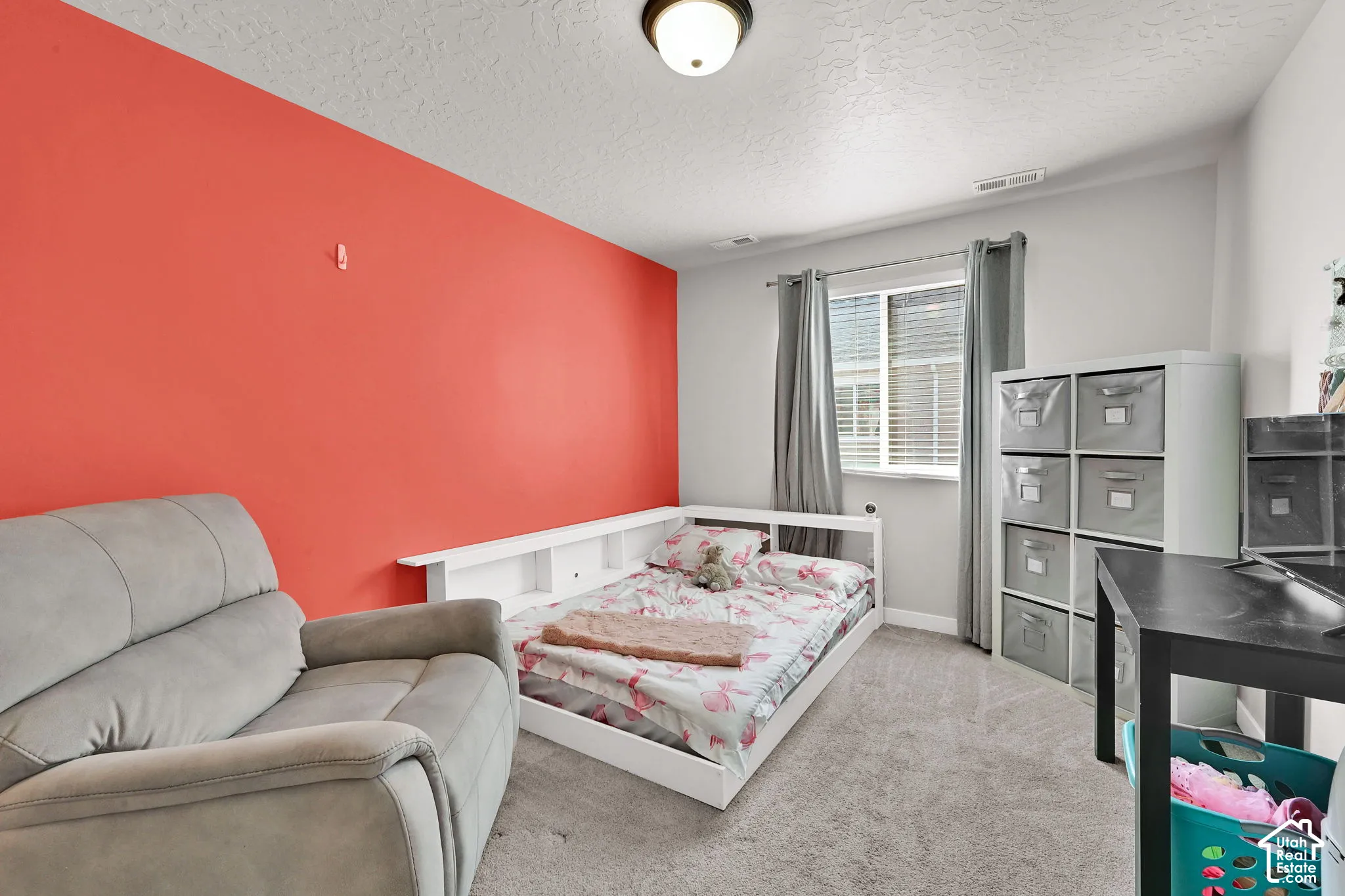 Room featuring neutral-toned carpeting, a vibrant accent wall, and a flush-mount ceiling light fixture