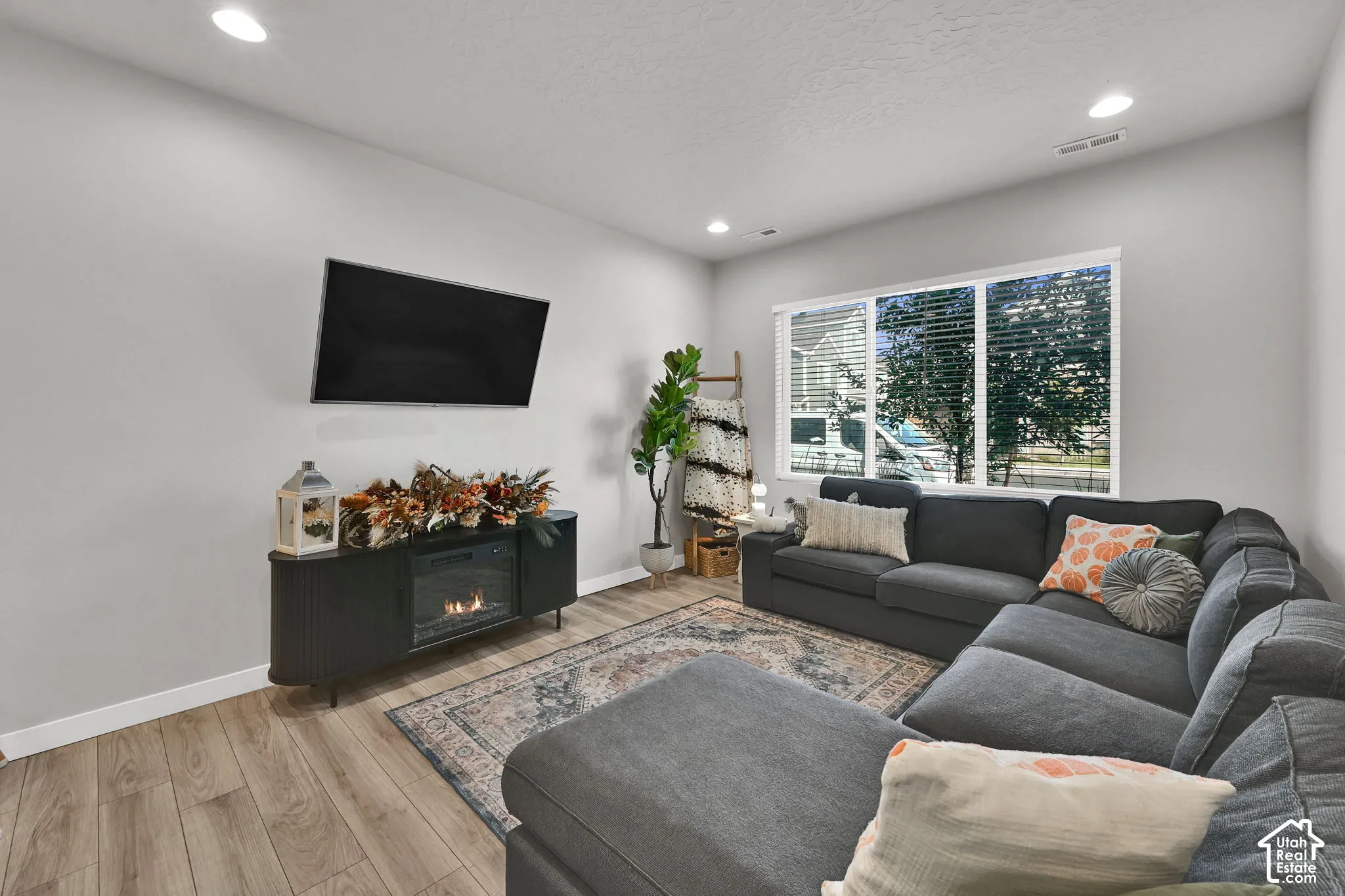 Living area featuring wood-finish flooring, recessed lighting, and a large multi-pane window