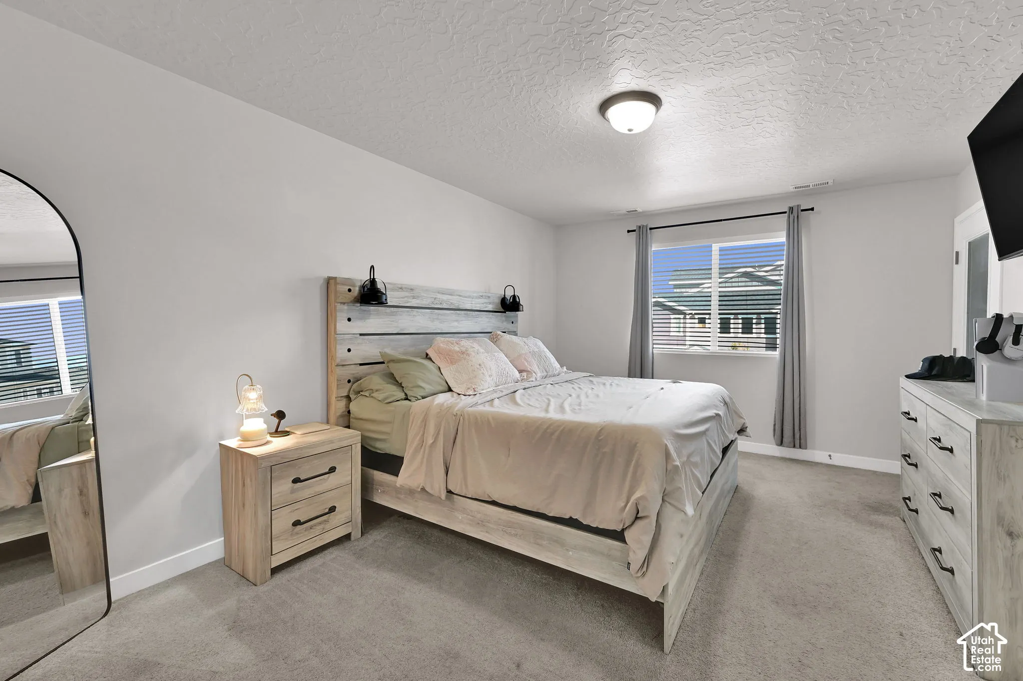 Neutral-toned interior space featuring light-colored wall-to-wall carpeting, a horizontal sliding window, and a central ceiling-mounted light fixture