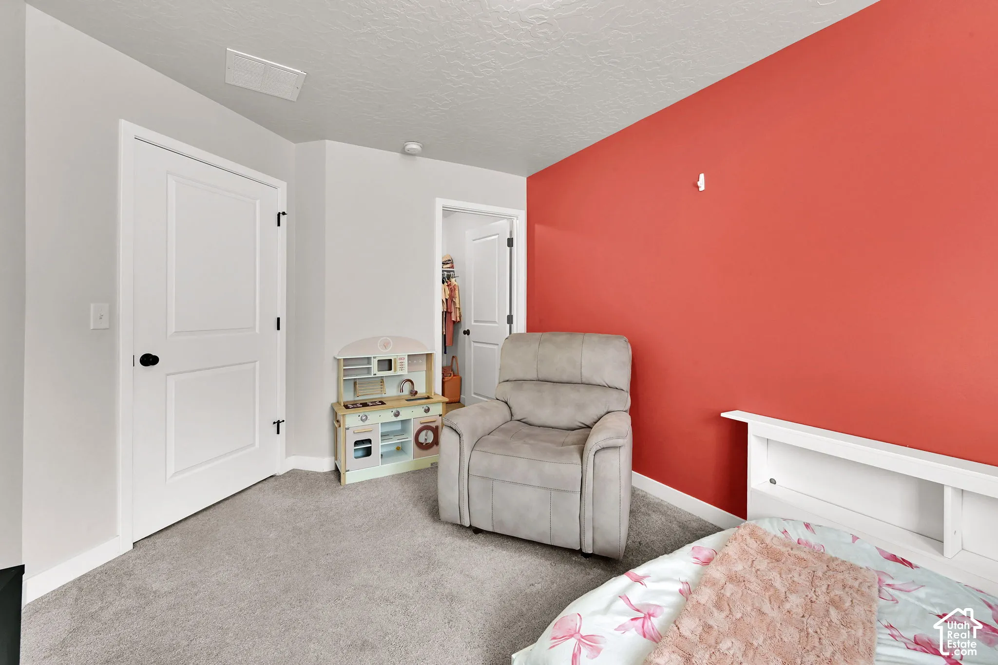 Interior room featuring neutral wall tones, a bold accent wall, wall-to-wall carpeting, and an integrated reach-in closet