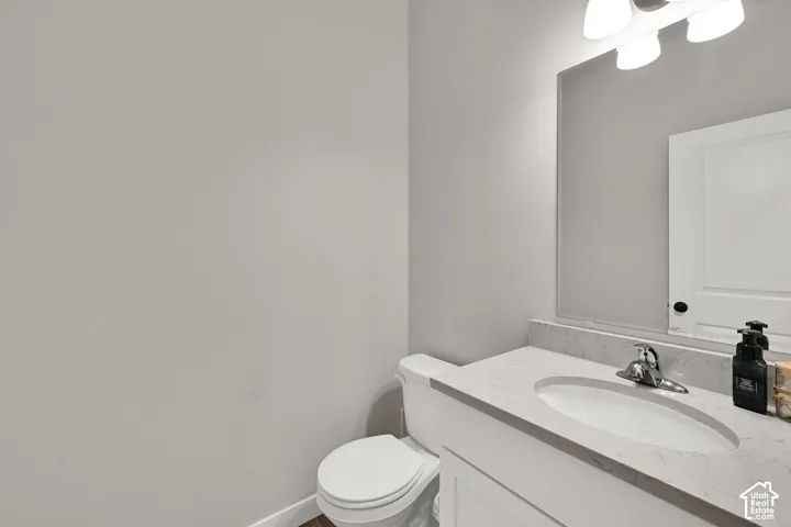 Single-sink vanity with a solid-surface countertop, integrated oval basin, polished chrome faucet, large-format wall mirror, and overhead tri-light fixture