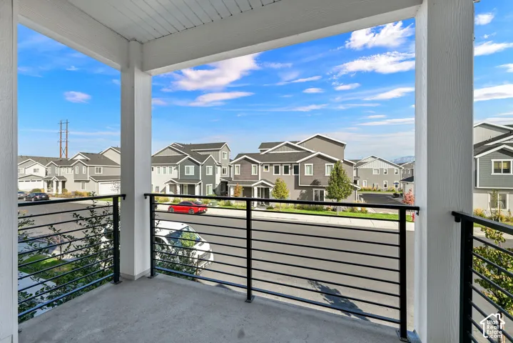 Covered balcony featuring concrete flooring, white structural columns, and a black metal horizontal-bar railing