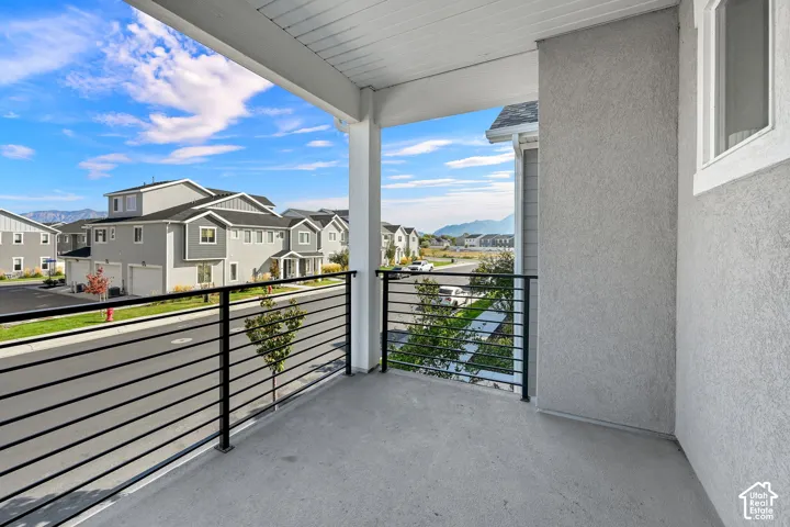 Covered balcony featuring concrete flooring, black metal railing, and a white ceiling finish