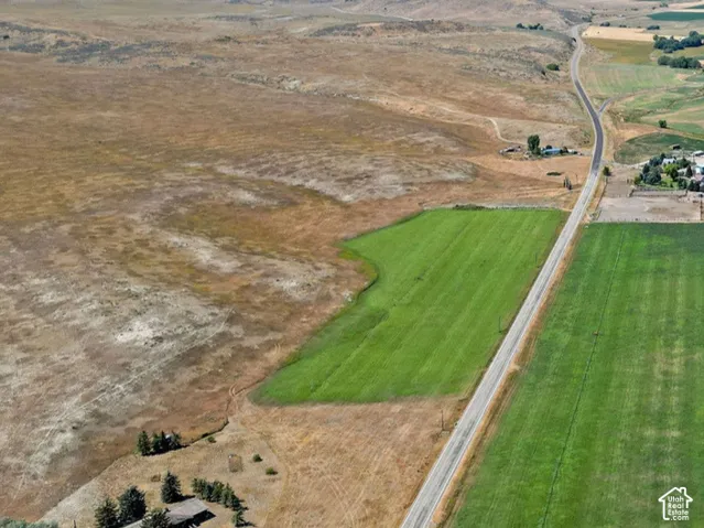 Aerial perspective of expansive acreage featuring vast agricultural land, irrigated fields, and a prominent mountain range backdrop