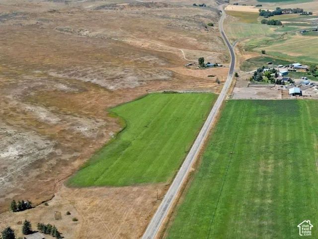 Aerial perspective of expansive acreage featuring vast agricultural land, irrigated fields, and a prominent mountain range backdrop
