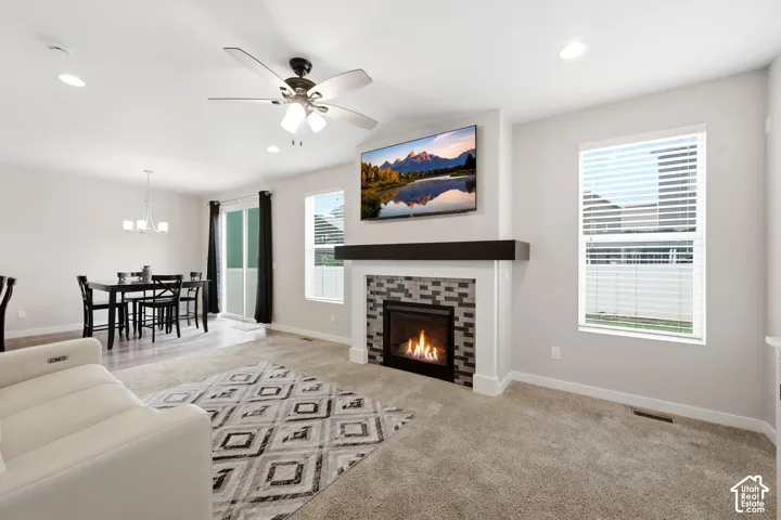 Recessed lighting and ceiling fan, gas fireplace with tile surround and dark wood mantel, carpeted flooring, and a sliding glass door