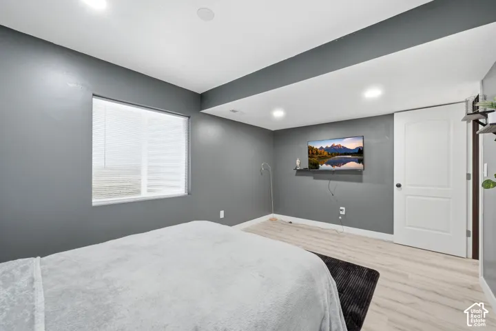 Recessed lighting, wood-finish flooring, and a window with blinds