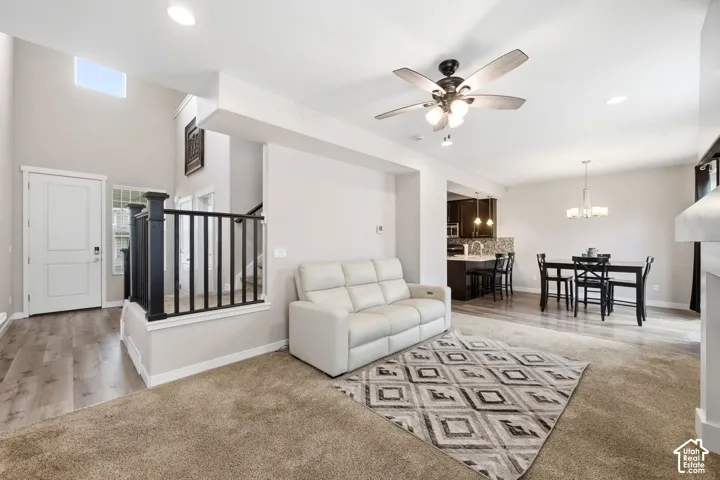 Open-concept living space with wood-finish flooring, recessed lighting, a ceiling fan, and a built-in kitchen island with pendant lighting