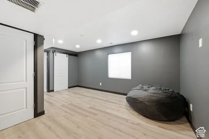 Recessed lighting, wood-finish flooring, dark accent walls, white interior doors, and a sliding barn door