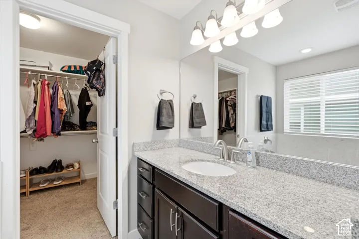 Vanity with light-toned countertop, dual-basin sink, and dark wood-finish cabinetry