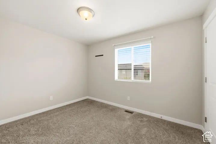 Textured carpeting with light-toned walls, a single window with blinds, and a flush-mount ceiling light fixture