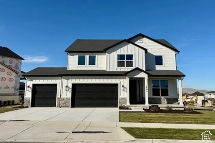 Modern farmhouse exterior with board and batten siding, stone accents, dark-framed windows, a two-car garage, and a covered porch