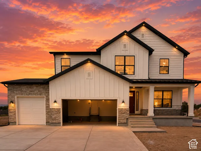 Modern farmhouse exterior showcasing a two-story design with white board-and-batten siding, multiple gabled rooflines, and stone-clad foundation accents