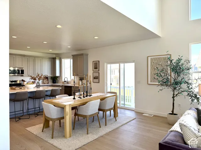 Open-concept living area featuring wood-finish flooring, a kitchen island with seating, stainless steel appliances, and a sliding glass door