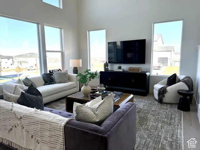 High ceilings with expansive windows, wood-finish flooring, and a built-in media console