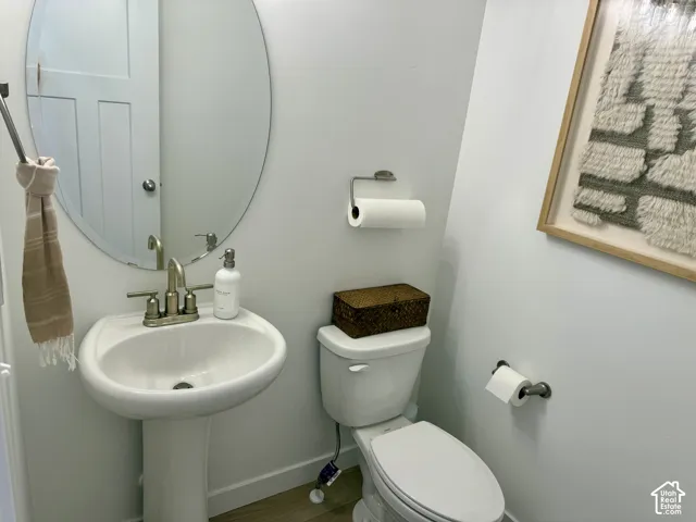Pedestal sink with brushed nickel faucet, oval mirror, and toilet