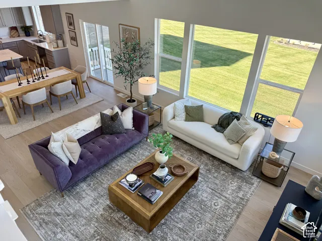 Light wood-finish flooring throughout, a modern kitchen with gray cabinetry, a spacious open-concept living area, and large windows