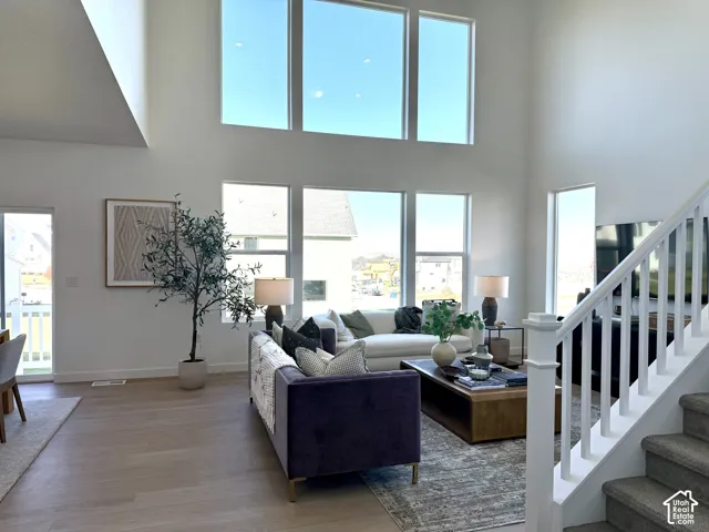 Two-story living area with high ceilings, multiple large windows, and light wood-finish flooring
