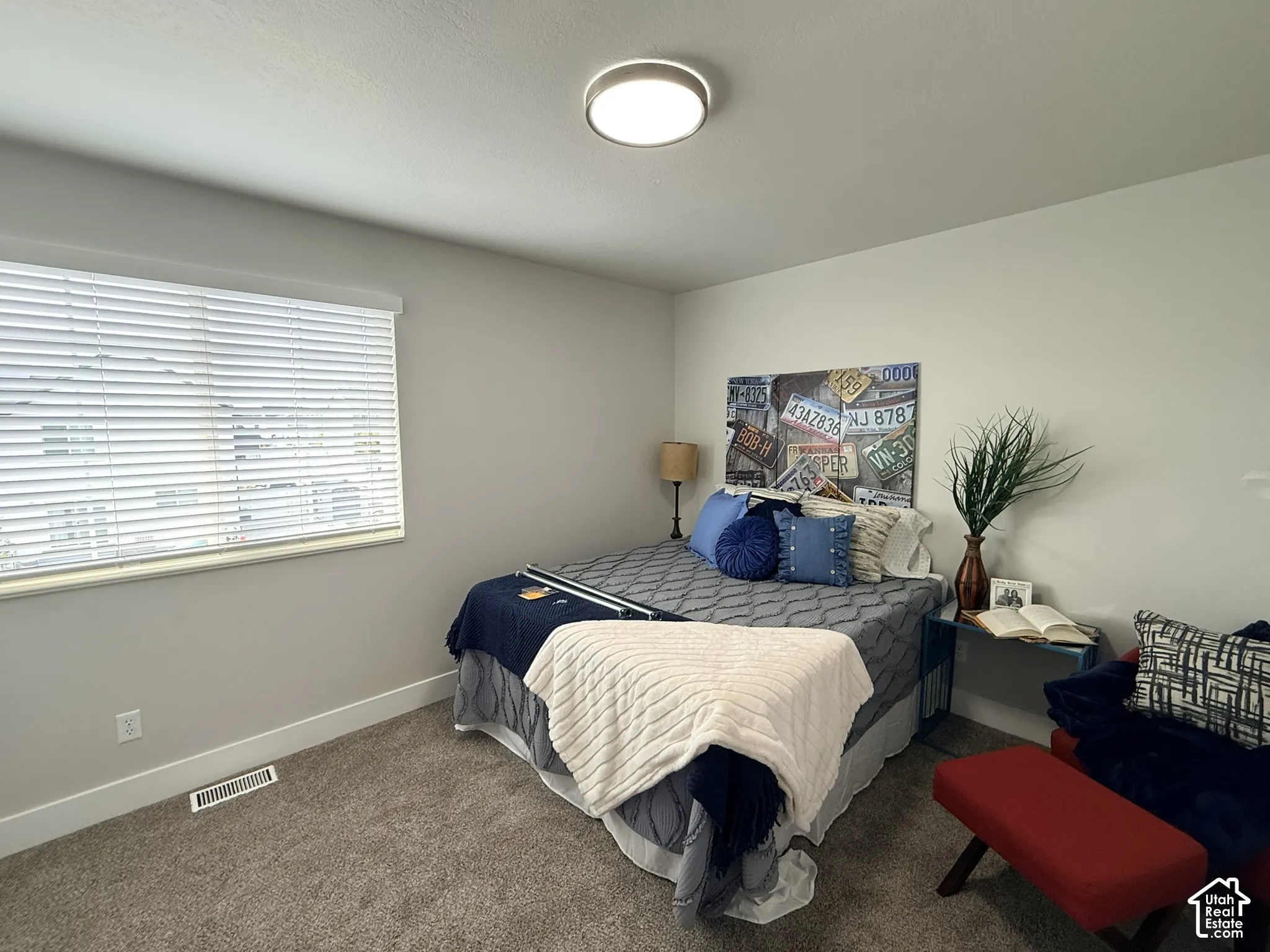 Neutral-toned interior space featuring neutral wall-to-wall carpeting, crisp white wall finish, and a flush-mount circular LED light fixture
