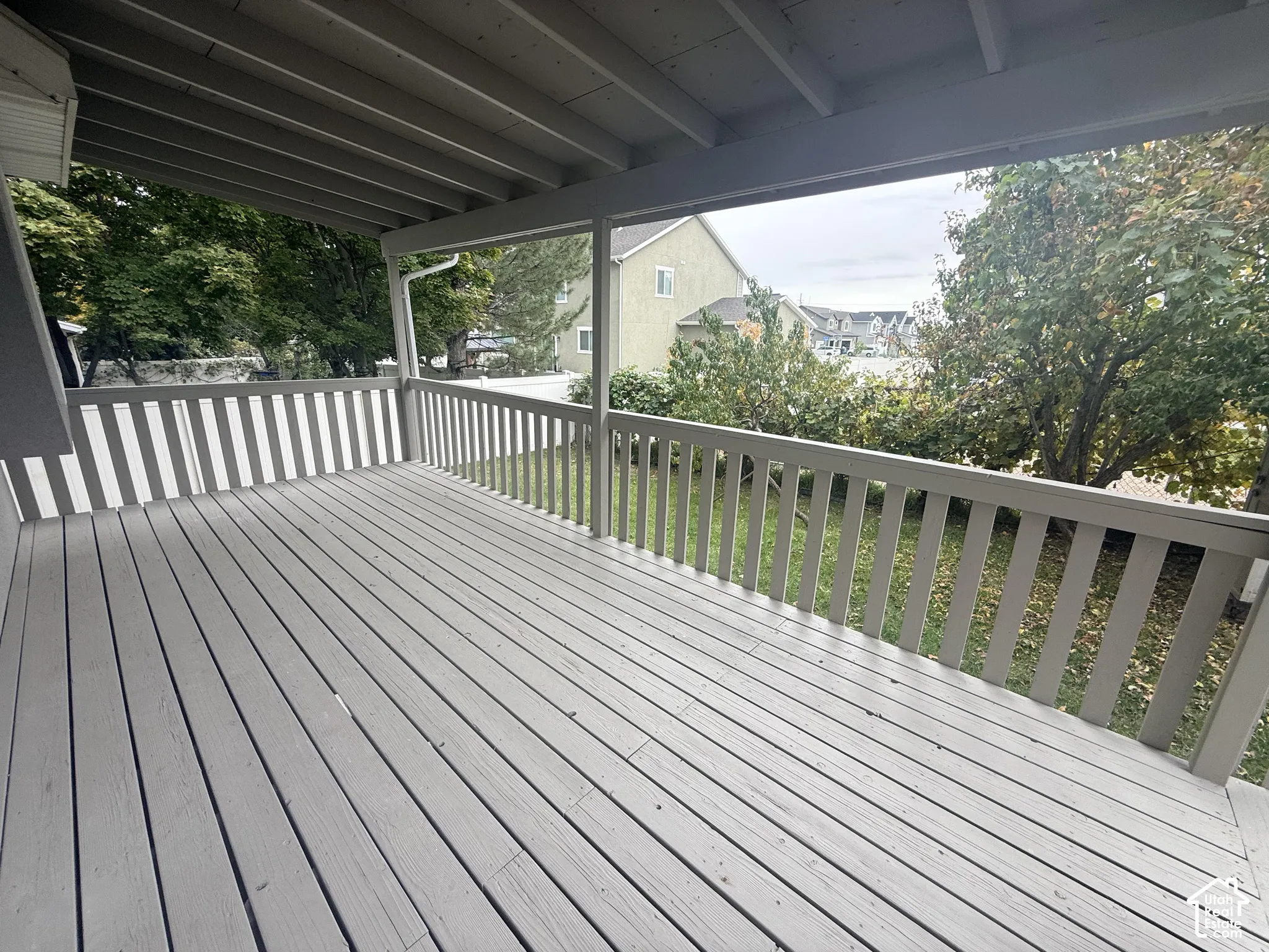 Covered deck featuring wood-finish decking, painted wooden railings, and exposed rafter ceiling