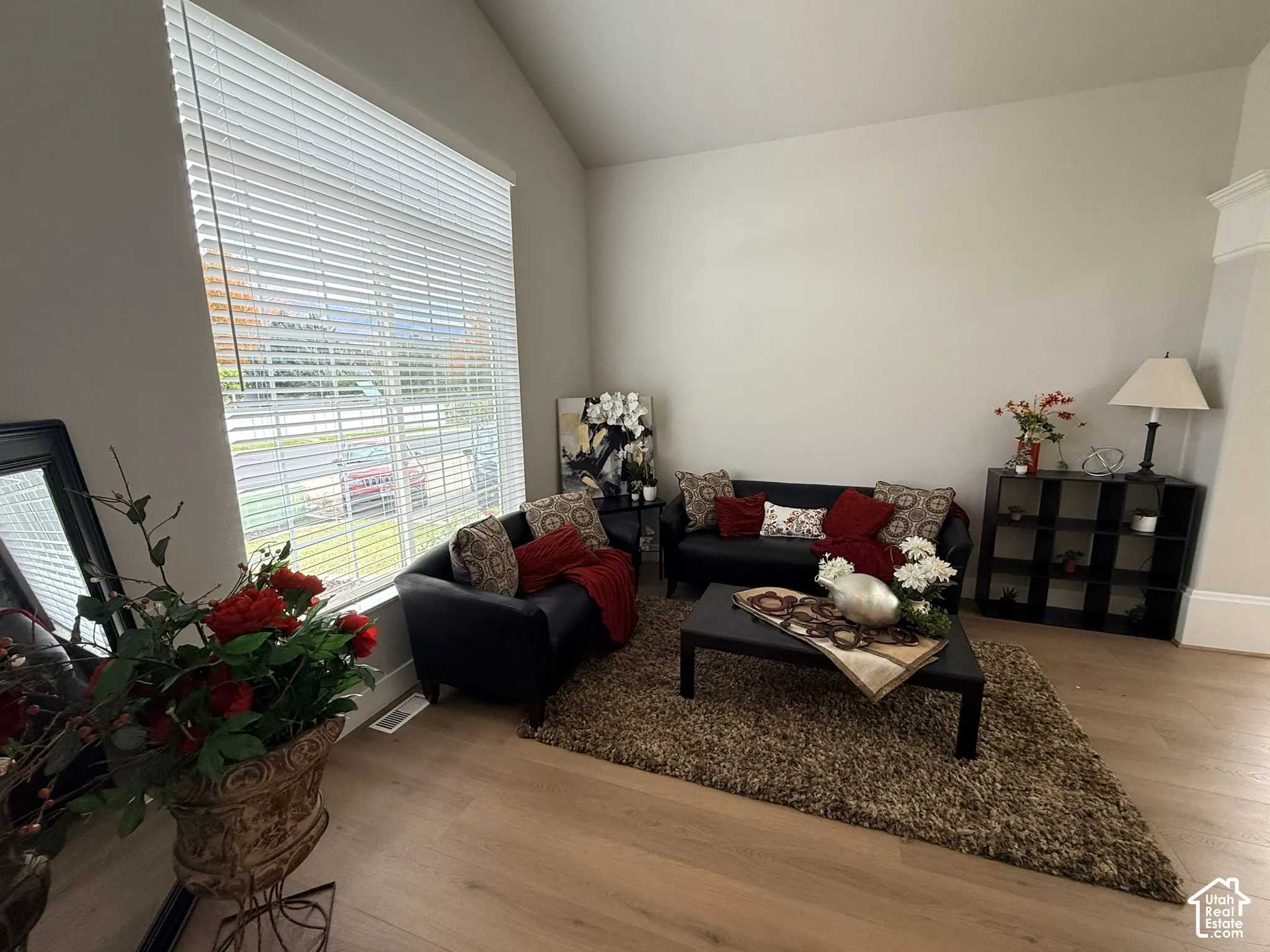 Vaulted ceilings, large window with horizontal blinds, and wood-finish flooring