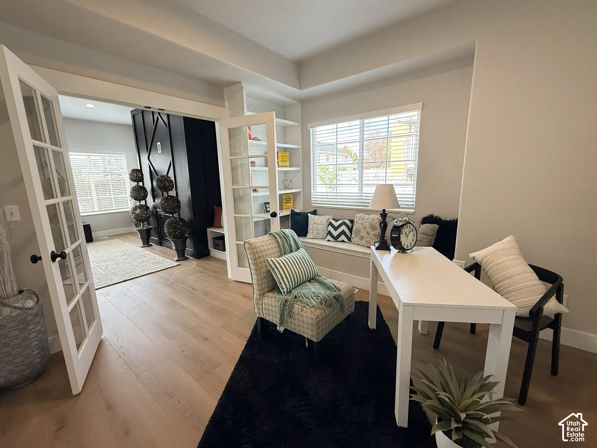 Wood-finish flooring, built-in shelving, glass-paneled French doors, and a built-in window bench