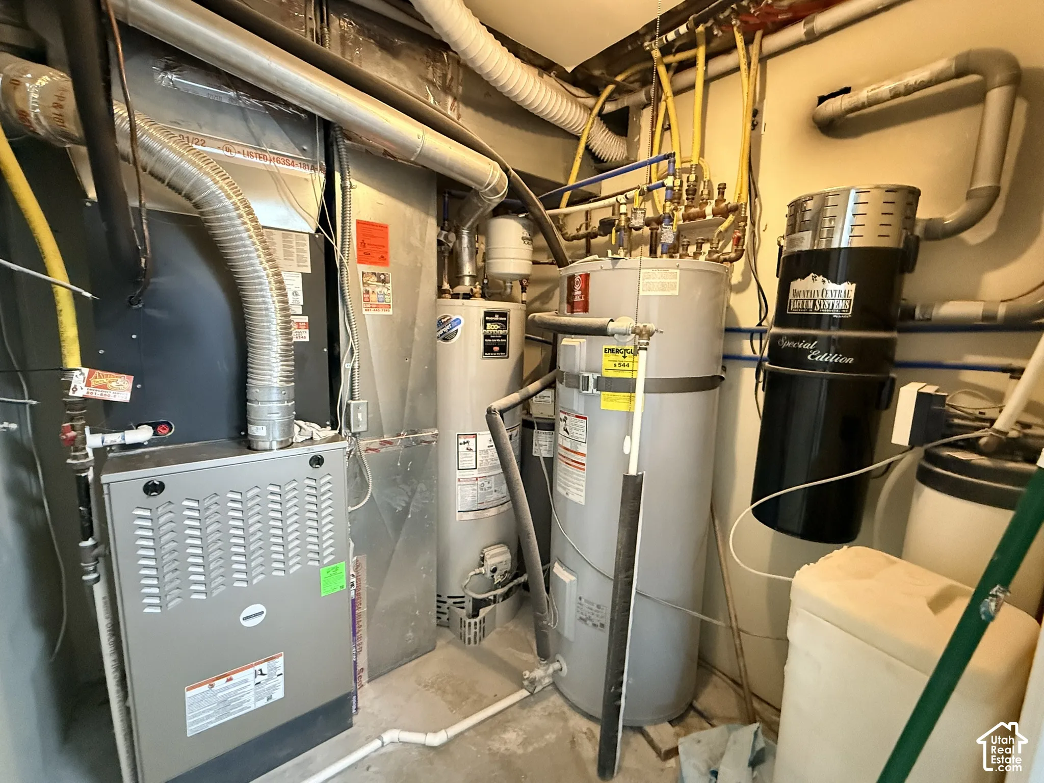 Mechanical utility room featuring a high-efficiency forced-air furnace, dual water heaters, integrated central vacuum system, and water filtration components