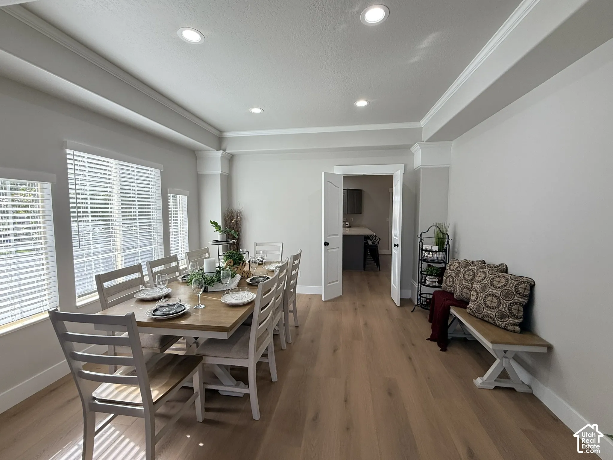 Dining area featuring tray ceilings, recessed lighting, wood-finish flooring, and multiple windows with horizontal blinds