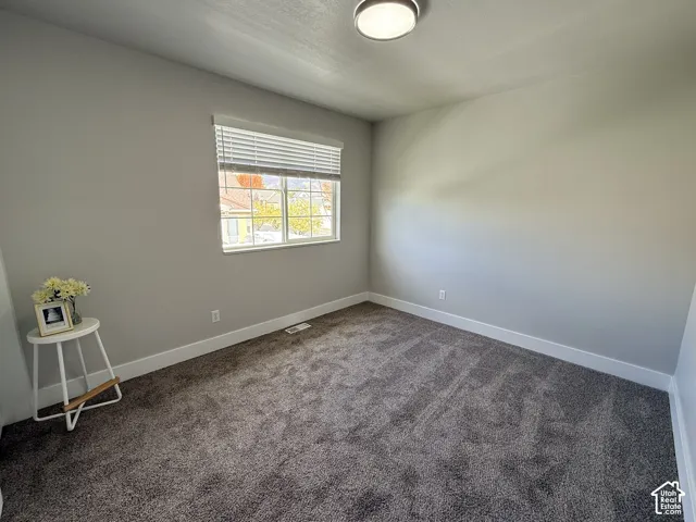 Neutral wall tones, wall-to-wall carpeting, window with slatted blinds, and a flush-mount ceiling light fixture