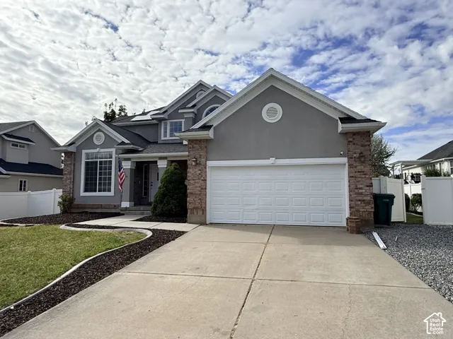 Exterior featuring a stucco facade with brick masonry accents, a multi-gabled roofline, and a multi-car attached garage