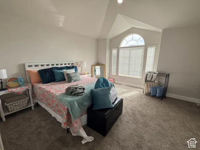 Vaulted ceiling, arched window with multi-pane transom, neutral wall coloring, and carpeted flooring