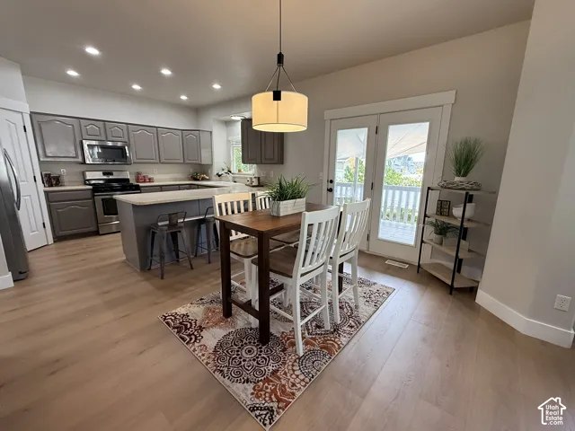 Kitchen featuring grey cabinetry, peninsula with stone-finish countertop, recessed lighting, wood-finish flooring, and glass-paneled double doors