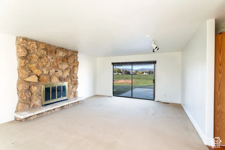 Living area featuring a floor-to-ceiling natural stone fireplace with a stone hearth, sliding glass doors, and track lighting