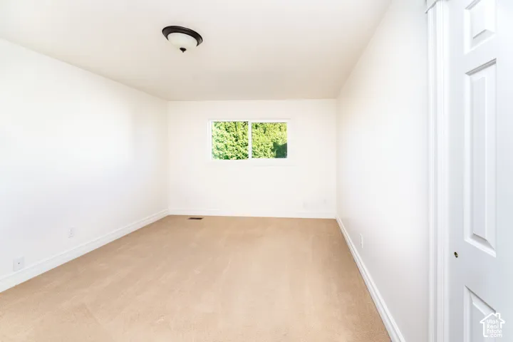 Neutral interior room featuring neutral carpeting, a dual-pane sliding window, and a white six-panel closet door